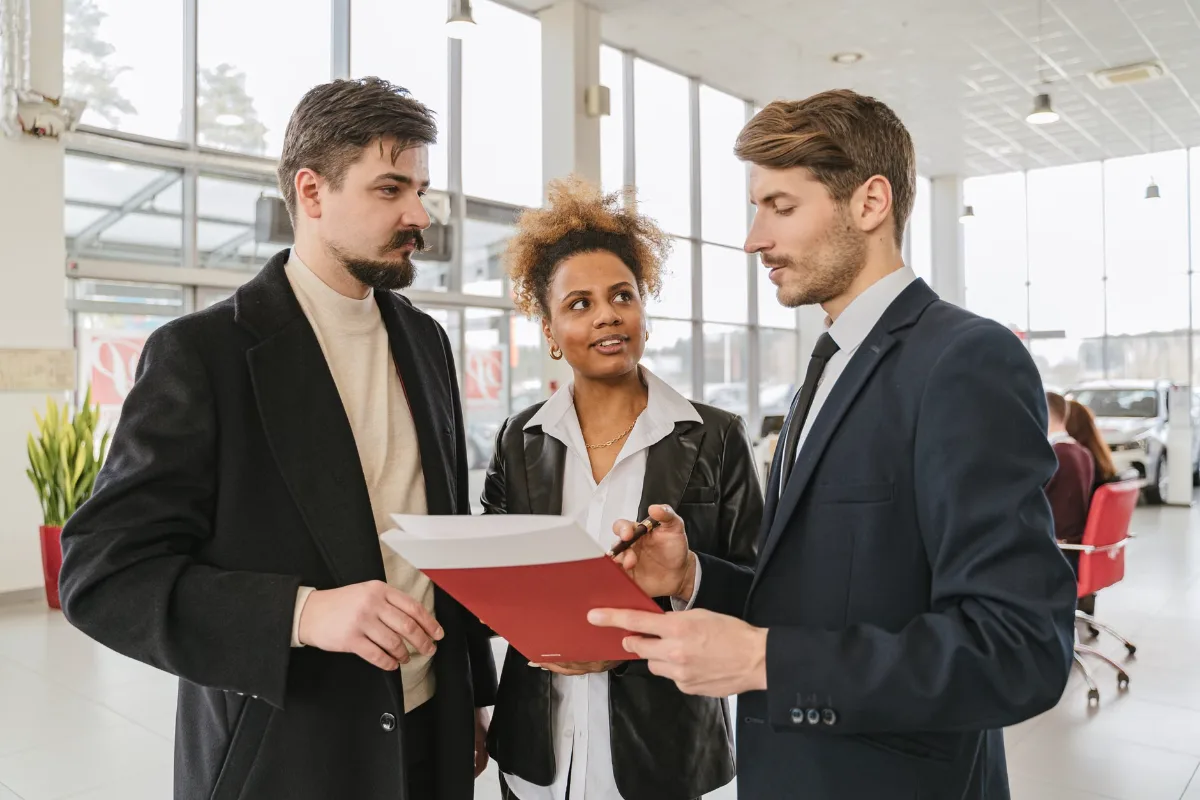 Business professionals discussing a car lease or purchase agreement in a showroom setting