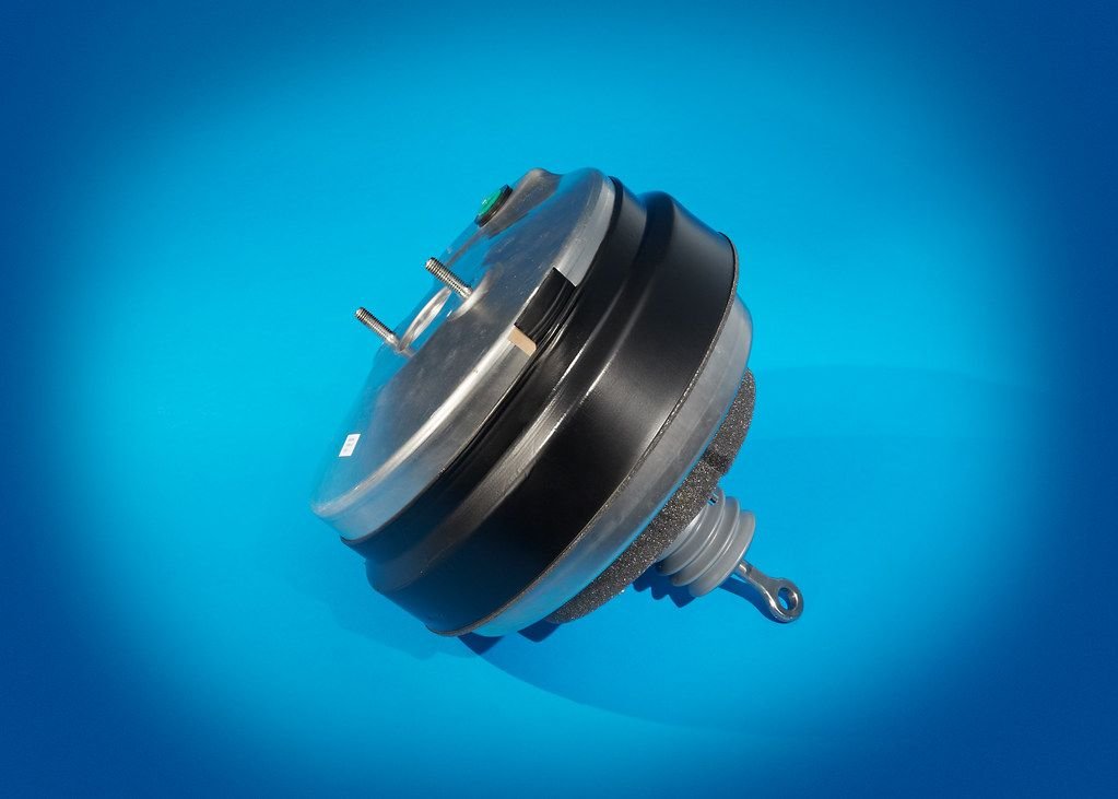 New vacuum brake booster unit on a blue background, the part priced in a brake booster replacement