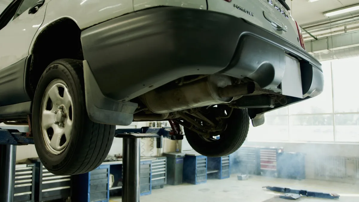 A vehicle elevated on a lift in an auto repair shop, ready for service