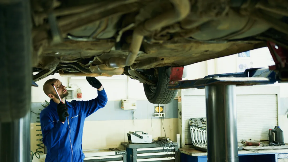 Mechanic inspecting the brake lines on the underside of a car on a lift