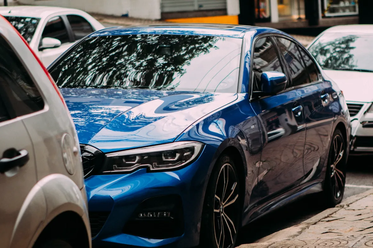 A vibrant blue luxury sedan parked on an urban street among cars