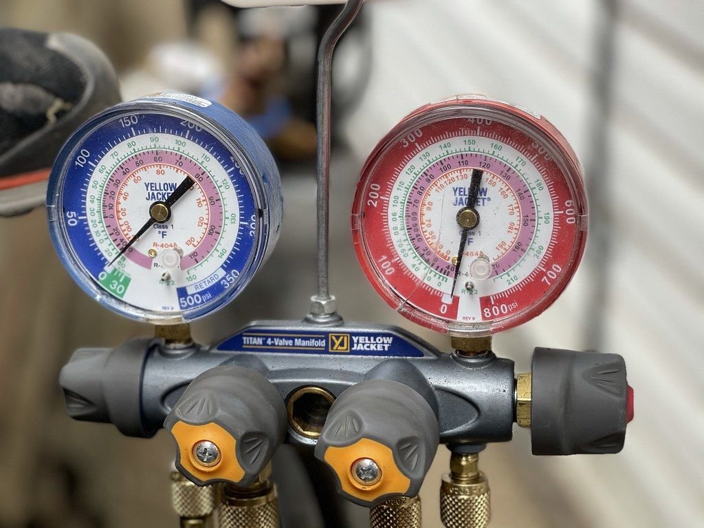 AC manifold gauge set used to check refrigerant pressure during a car AC leak repair