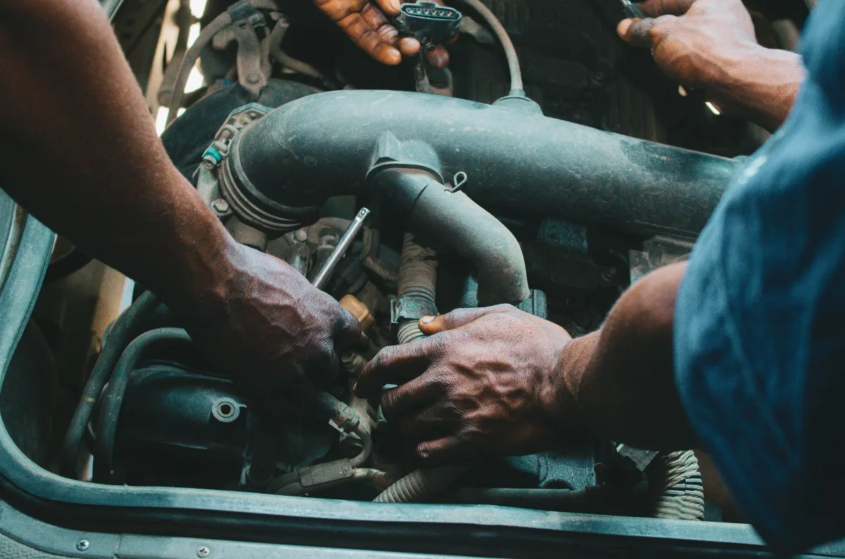 Close-up of mechanics working on a vehicle engine, showing teamwork and precision in car maintenance