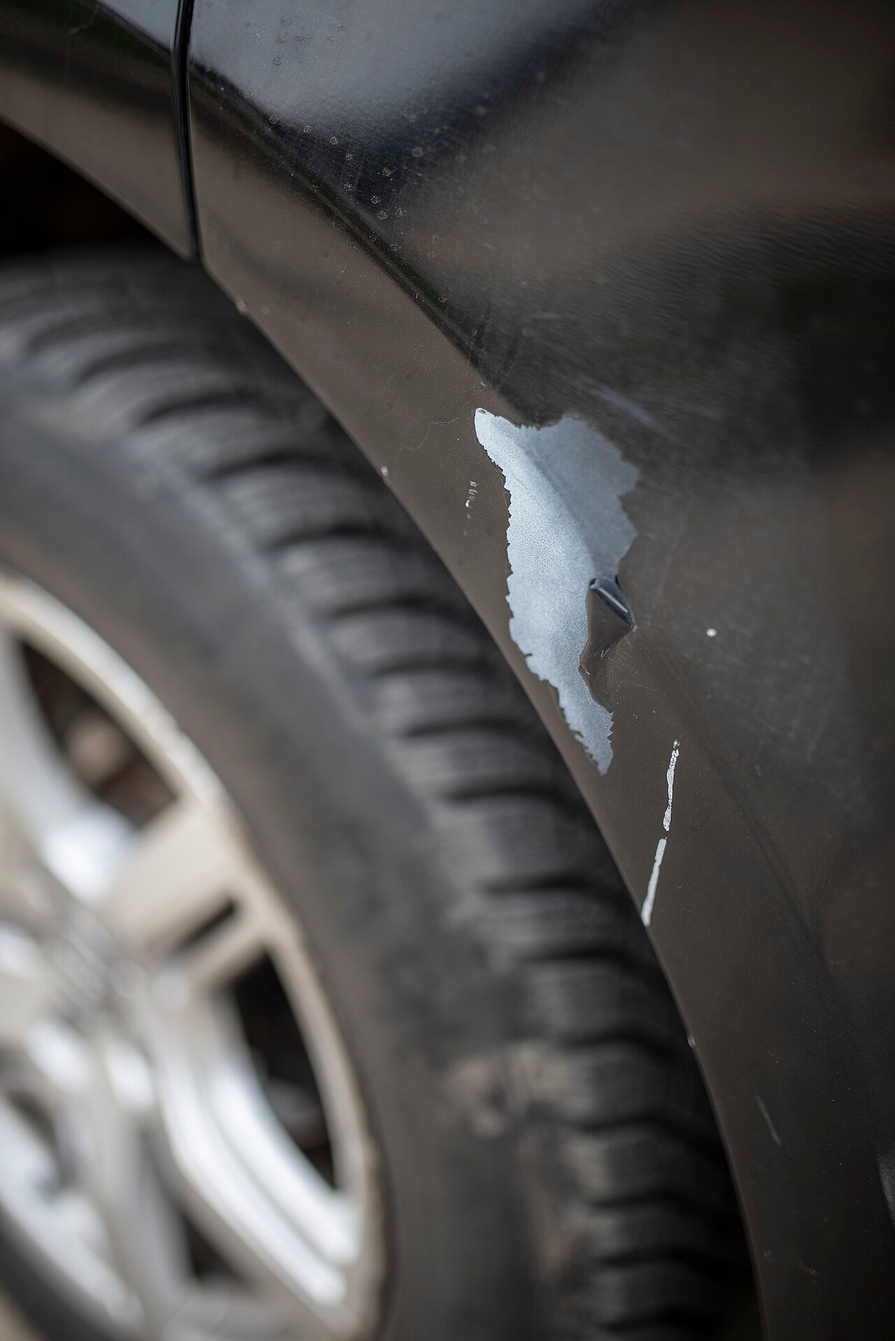 A scratched car fender in a parking lot