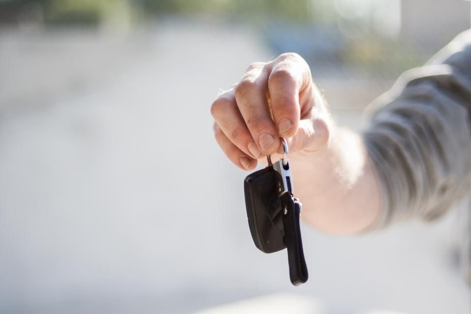 Hand holding out car keys, as when selling or trading in a car after engine failure