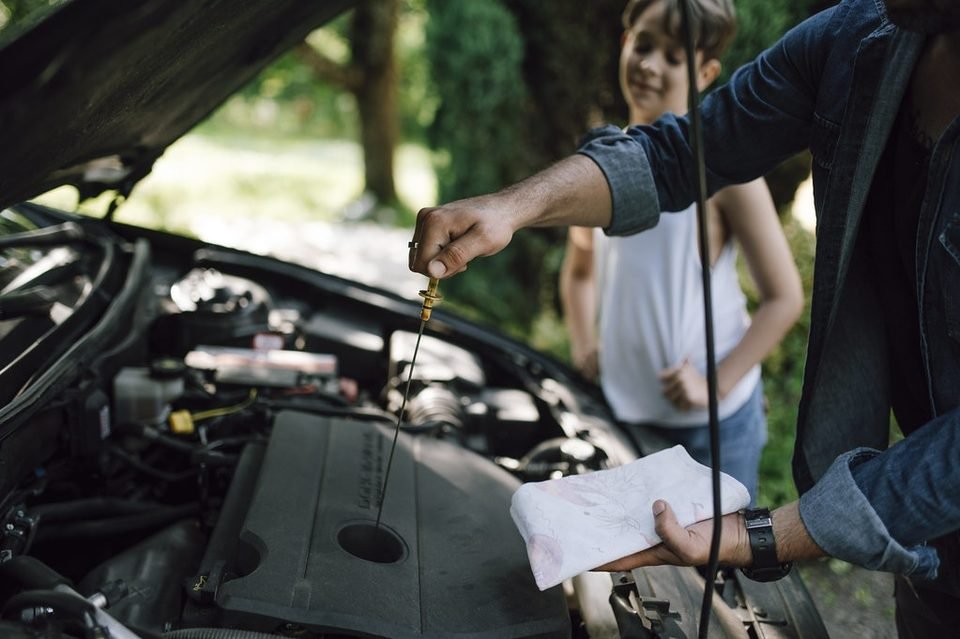 Mechanic checking the engine oil dipstick, one of the first checks for a blown head gasket