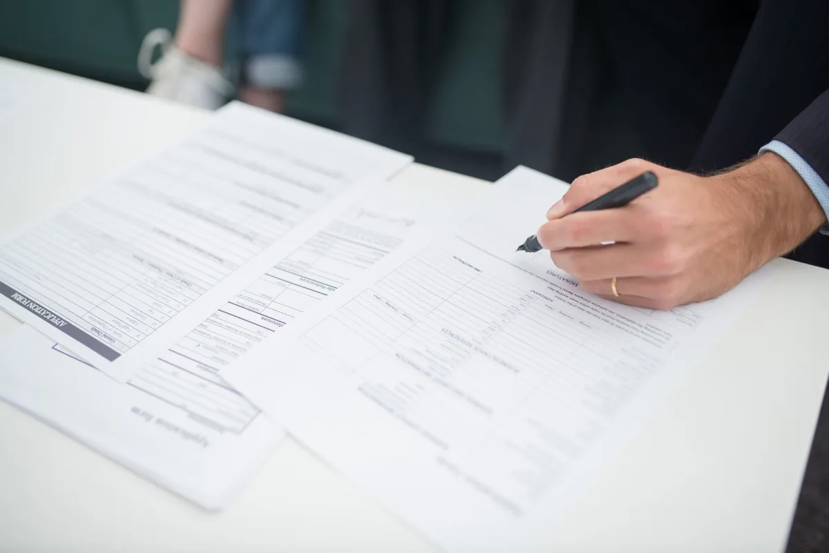 Close-up of a hand signing insurance documents in an office setting