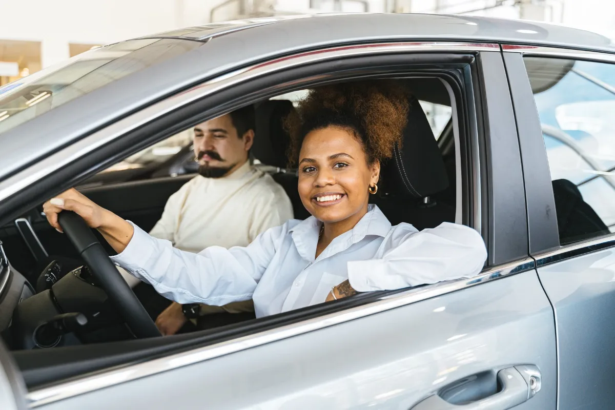 Happy interracial couple sitting in a new car showroom, enjoying their recent purchase