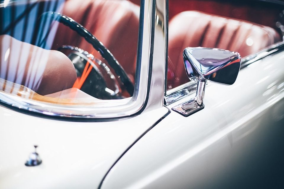 Close-up of a chrome side mirror on a classic car door